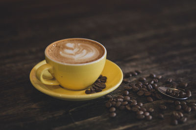 Coffee cup of latte art with coffee beans on wooden background