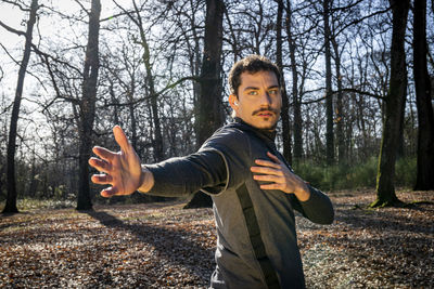 Runner is doing stretching in the woods. man with blue eyes and mustache is training in the park.