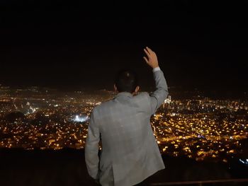 Rear view of man and woman standing in illuminated city against sky at night