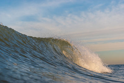 Sea waves splashing on shore against sky