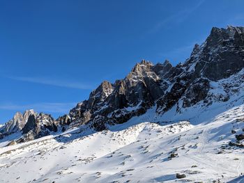 Scenic view of snow covered mountains against blue sky