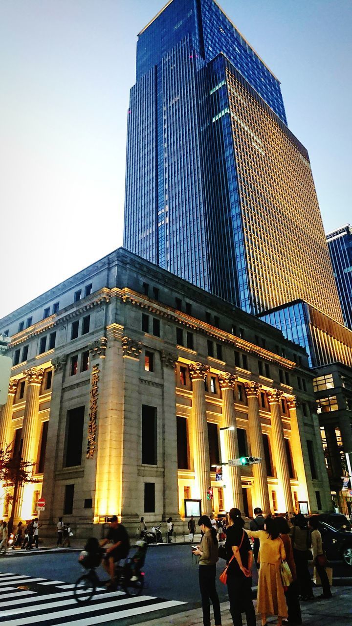 LOW ANGLE VIEW OF PEOPLE ON STREET AGAINST MODERN BUILDINGS