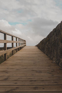 Surface level of wooden footbridge against sky