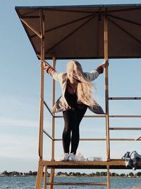 Portrait of woman standing on lifeguard hut at beach