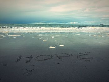 Scenic view of beach against cloudy sky