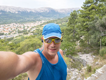 Portrait of young man wearing sunglasses while standing against mountain