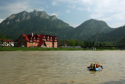 Scenic view of mountains in front of river against sky on sunny day