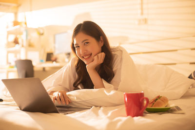 Young woman using mobile phone on bed