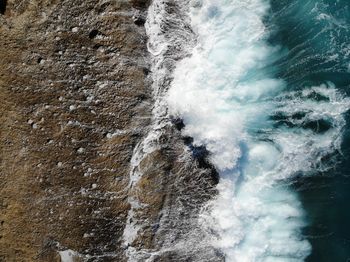 Drone shot of breaking waves on rocks.