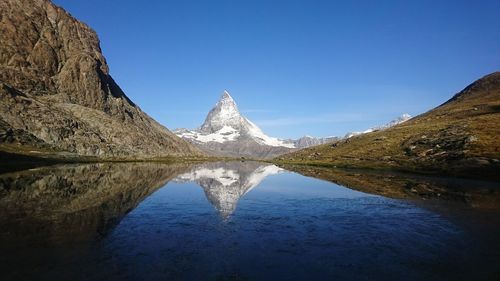 Reflection of mountain in lake against clear blue sky