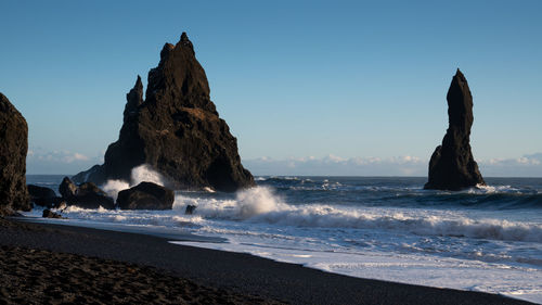 Rock formations on beach against clear sky