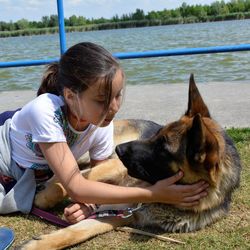 Young woman with dog sitting by water