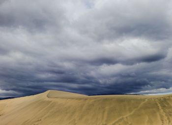 Scenic view of desert against cloudy sky