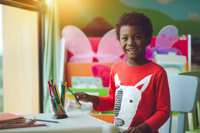 Portrait of smiling boy sitting on table