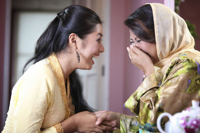 Side view of mother and daughter laughing at home