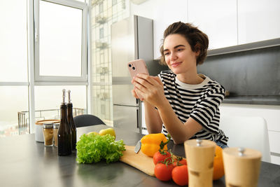 Portrait of young woman using mobile phone at home