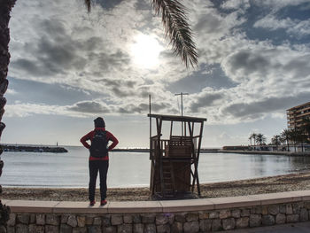 Rear view of man standing by sea against sky
