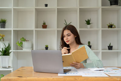 Portrait of young woman using digital tablet on table