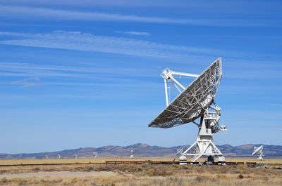 Parabolic antenna on field against sky