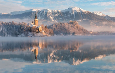 Scenic view of lake by snowcapped mountains against sky