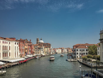 Boats in canal against clear blue sky