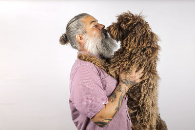 A bearded man kisses and hugs his water dog. love between owner and dog. isolated on whte