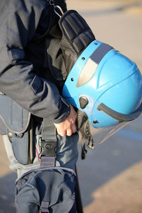 Midsection of man holding helmet on footpath