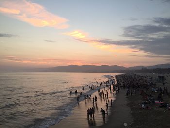 High angle view of people at beach against sky during sunset