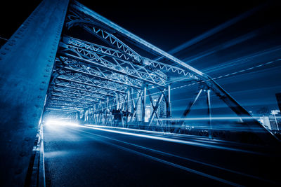 Illuminated bridge against blue sky at night