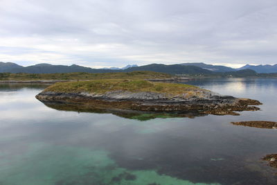 Scenic view of lake by mountains against sky