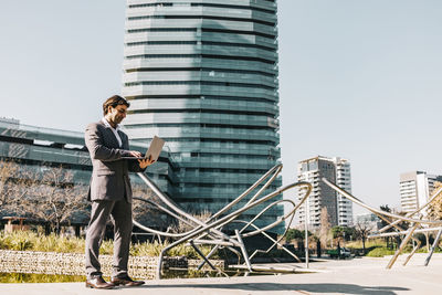 Man standing by modern building against sky in city