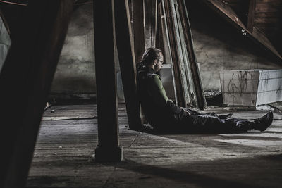 Side view of woman sitting on abandoned floor