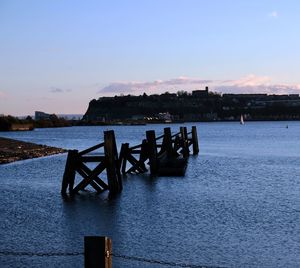 Pier on lake against sky during sunset