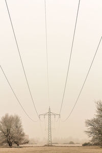 Electricity pylon on field against clear sky