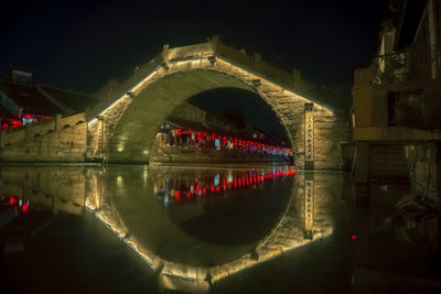 Illuminated bridge over river at night