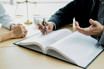 Midsection of woman reading book on table