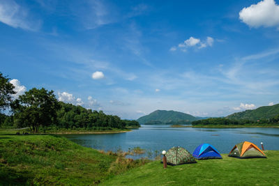 Tents by lake against blue sky