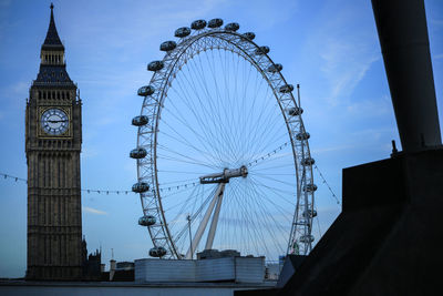 Low angle view of millennium wheel and big ben against sky in city