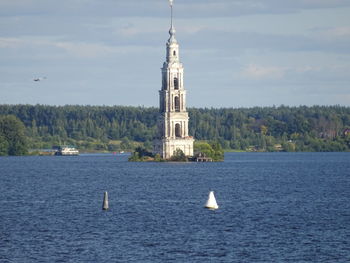 Sailboat in sea by building against sky