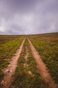 Road amidst field against sky