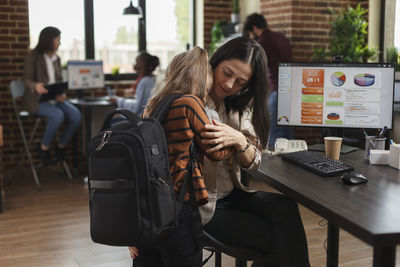 Young woman using mobile phone while sitting at cafe