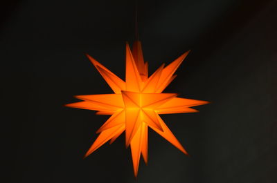 Close-up of illuminated christmas decorations on table against black background