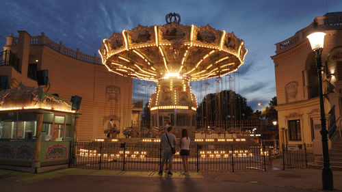 People at illuminated amusement park at night