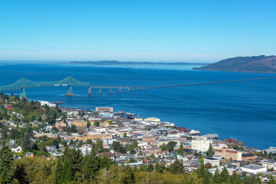 High angle view of city by sea against clear blue sky