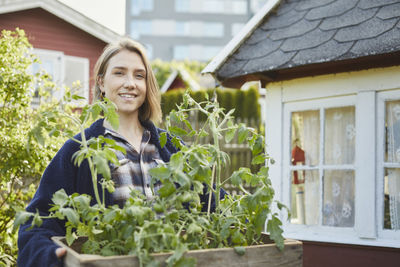 Woman holding crate with tomato plants