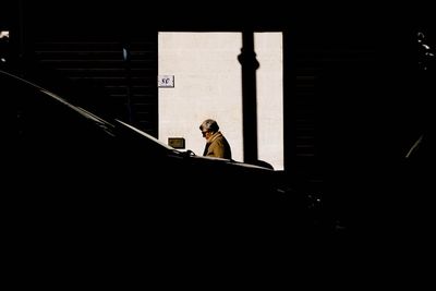 Side view of man sitting on wall