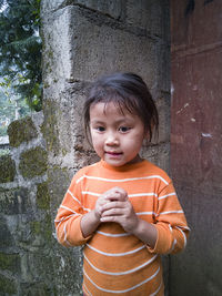 Portrait of boy standing against wall