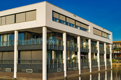 Appartement building surrounded by water against blue sky