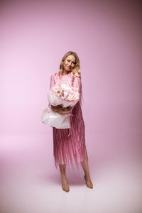 Portrait of young woman standing against wall
