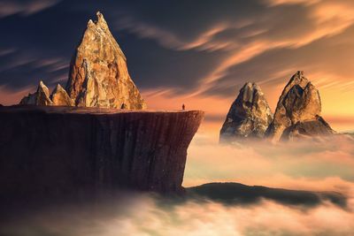 Rock formation on snow against sky during sunset